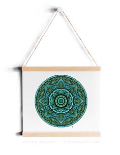 a blue and green circular artwork hanging on a white wall next to a wooden frame