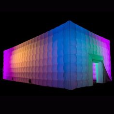 an inflatable building is lit up at night with colorful lights on the side