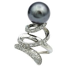 Ring Size: 7 This captivating black pearl and diamond cocktail ring boasts a mesmerizing spiral design and set in luxurious 18 karat white gold. At its heart lies a lustrous black pearl, exuding an aura of mystery and sophistication. Paired with the pearl, a dazzling array of diamonds trace a graceful spiral, accentuating its beauty with every curve. This exquisite ring is a testament to refined craftsmanship and timeless elegance, perfect for making a statement at any event. This piece is in very good estate condition and has been professionally cleaned and polished. Metal: 18 Karat White Gold Gemstones: Black Pearl and Diamonds Pearl Count: 1 Pearl Shape: Round Pearl Color: Black Diamond Cut: Round Diamond Total Carat Weight: 0.20 carats Diamond Color: H - I Diamond Clarity: SI2 Ring Wei Diamond Cocktail Ring, Diamond Cocktail Rings, Spiral Design, Pearl Diamond, Diamond Color, Pearl Color, Black Pearl, Cocktail Ring, Diamond Clarity