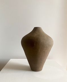 a brown vase sitting on top of a white table