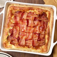 a bacon and cheese casserole in a white dish on top of a wooden table