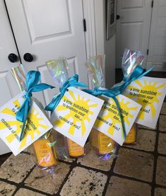 four small bottles with yellow and blue ribbons tied around them on a tile floor next to a door