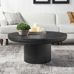 a living room with white couches and two candles on top of the coffee table