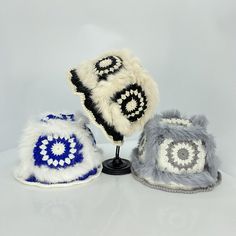 three hats are sitting on top of a small display stand, one is white and the other is blue