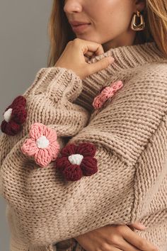 a woman wearing a sweater with crochet flowers on it