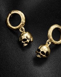 two gold skull charms sitting on top of a black surface