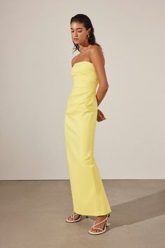 a woman in a yellow strapless dress poses for the camera with her hand on her hip