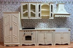 a doll house kitchen with white furniture and floral wallpaper