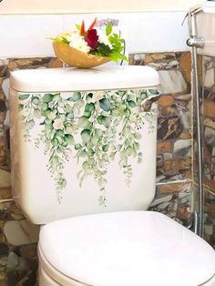 a white toilet sitting in a bathroom next to a wall with plants painted on it