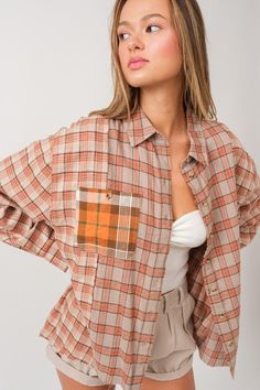 a woman with her hands on her hips, wearing shorts and a shirt that has an orange plaid pattern