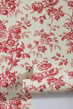 a red and white wallpaper with floral designs on the side, next to a pair of scissors