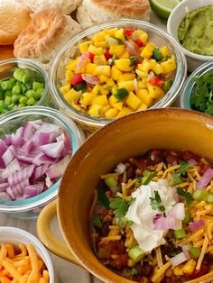 several bowls filled with different types of food on top of a table next to bread