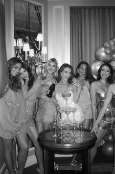 a group of women standing next to each other in front of a table with a cake on it