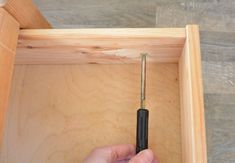 a person holding a screwdriver in a wooden box