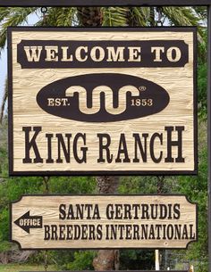 a sign for king ranch in santa gertrudis, california with palm trees behind it