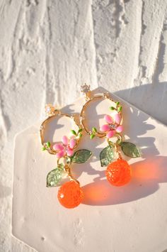 "AMALFI crown translucent tangerine orange earrings, czech glass tangerine earrings, food earrings, mandarin fruit earrings, custom earrings These Tangerine Crown of Flowers Gold Plated Earrings are a stunning piece of jewelry that will instantly elevate any outfit. The earrings feature delicate gold plating that forms a crown-like design, adorned with beautiful flowers and leaves. The centerpiece of the earrings is a dazzling transluscent tangerine orange( or mandarin) Czech crystal, adding a pop of color and sparkle to the design. These earrings have a timeless elegance that will transport you to the picturesque Amalfi Coast in Italy with every wear. Whether you're dressing up for a special occasion or simply adding a touch of glamour to your everyday look, these earrings are sure to tur Cute Orange Jewelry For Party, Cute Orange Party Jewelry, Orange Dangle Flower Earrings Gift, Orange Dangle Flower Earrings For Gift, Nickel Free Orange Jewelry For Party, Nickel-free Orange Jewelry For Party, Orange Dangle Flower Earrings With Ear Wire, Orange Drop Earrings For Gift, Cute Orange Dangle Jewelry