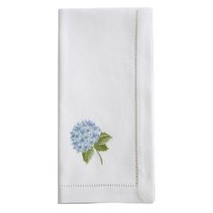 a white towel with blue flowers and green leaves on the front, sitting on a white surface