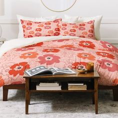 a bed with an orange and pink flowered comforter set on top of it