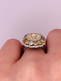 a close up of a person's hand holding an engagement ring with two yellow and white diamonds