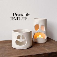 two white vases sitting on top of a wooden table with a candle in the middle