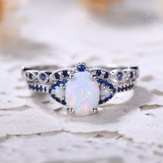 6x8mm Oval cut Opal engagement ring set in white gold. The stones are Opal and lab blue sapphire. This ring can also be made in genuine solid 10k, 14k, 18k gold or Platinum, and all the rings in my shop can be customized too! If you want to know more details about the ring, just contact with me anytime! If you want to customize the ring, just contact with me anytime! If you want to make a custom jewelry, just contact with me anytime! PROCESS TIME AND SHIPPING It usually takes about 3-4 weeks to Opal And Saphire Ring, Blue Sapphire Wedding Ring Set, Opal Wedding Ring Set, Ring Redesign, Sapphire Wedding Ring Set, White Opal Engagement Ring, Redesign Ideas, Blue Sapphire Wedding Ring, Sapphire Wedding Ring