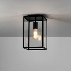 a light fixture hanging from the ceiling in a room with white walls and flooring