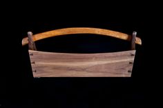 a wooden cutting board with handles on a black background in front of a dark backdrop