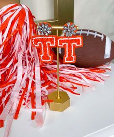 an orange and white streamer next to a football on top of a wooden stand