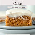 a piece of carrot cake on a plate with a fork and milk jug in the background