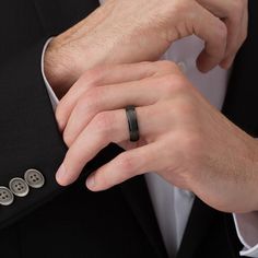 a man in a tuxedo adjusting his black wedding band