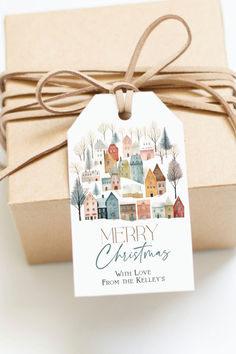 a gift wrapped in brown paper with a tag that says merry christmas and houses on it