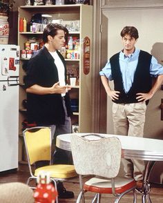 two men standing in a kitchen talking to each other