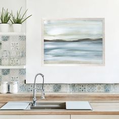 a painting hanging on the wall above a kitchen sink with a faucet next to it