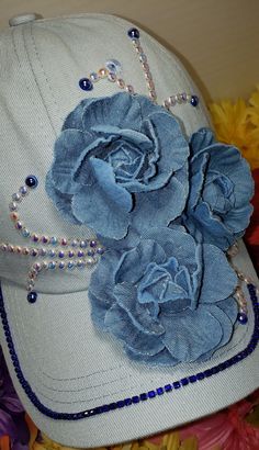 a white hat with blue flowers and pearls on the brim, sitting next to yellow flowers