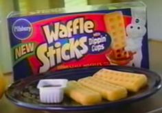 waffle sticks are on a plate with dips and orange juice in the background