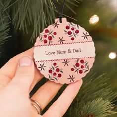 a hand holding a christmas ornament that says love mum and dad