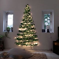 a christmas tree is lit up in the corner of a room with lights on it