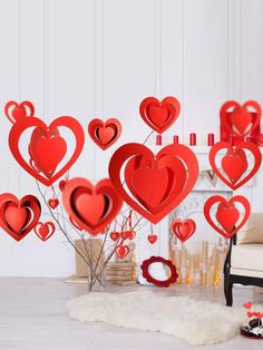 a bunch of red hearts hanging from the ceiling in front of a fireplace with candles