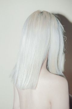 the back of a woman's head with long white hair and no shirt on