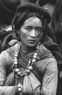 an old black and white photo of a woman in native clothing with beads on her neck