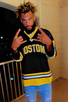 a man with dreadlocks standing in front of a door wearing a black and yellow jersey