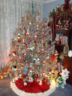 a white christmas tree in a living room next to a red and white blanket on the floor