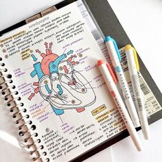 two pens are sitting on top of a notebook with an illustration of a heart and the inside of it