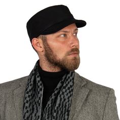 a man wearing a black hat and scarf with a gray blazer over his shoulders