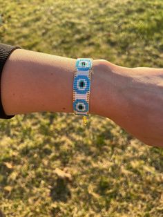 a person's arm with a blue and white beaded bracelet on top of it