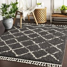 a black and white area rug with tassels on the floor in front of a chair