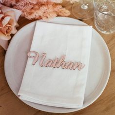 a napkin that says nathan on it sitting on top of a plate next to flowers