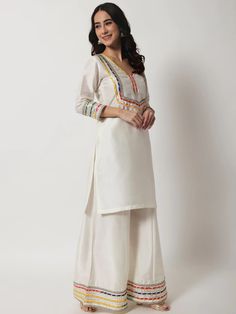 This is a beautiful 3 piece suit set. It comes with straight cut kurta has 3/4th sleeves, round neck, calf length teamed with croma silk palazzo pants and a multi color lehriya print organza dupatta with golden lace detailing. 3 piece set Color- Ivory Work- Gota & Embellished Detailing Kurti Length-34 inch Kurta Fabric-Croma Silk Bottom Fabric-Croma Silk Dupatta Fabric-Organza Sleeves-3/4th Sleeves Neck-Round Neck Care - Dry Clean