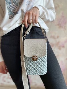 a woman is holding a white purse in her hand