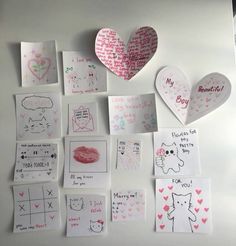 many hearts and handwritten notes are arranged on a table with other paper art pieces